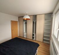 Schlafzimmer in einer 2-Zimmer-Wohnung mit Holzboden und Einbauschrank.