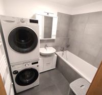 Badezimmer mit Badewanne, Waschmaschine und Trockner in einer 2-Zimmer-Wohnung.