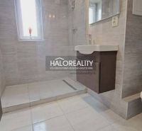 Badezimmer in einer 3-Zimmer-Wohnung mit Dusche und Waschbecken, Fliesen in hellen Farbtönen.