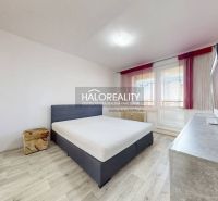 Schlafzimmer mit Bett, Fernseher und Holzboden in einer Zweizimmerwohnung.