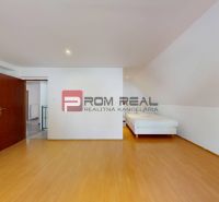 Ein Zimmer in einem Einfamilienhaus mit einem Bett und einem Boden in Holzoptik.