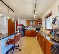 Küche in einem Einfamilienhaus mit Holzschränken, Fliesenboden und Pendelleuchten.