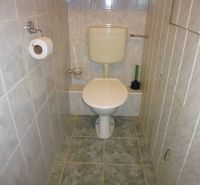 Badezimmer mit Toilette in einer 2-Zimmer-Wohnung mit gefliesten Wänden und Boden.