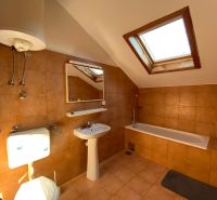 Badezimmer in einer Ferienwohnung mit Badewanne und Dachfenster.