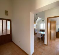 Flur in einer Ferienwohnung mit Keramikboden, Essbereich und Zimmer im Hintergrund.