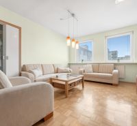 Wohnzimmer in einer 3-Zimmer-Wohnung mit einer Eckcouch und einem Boden in Holzoptik.
