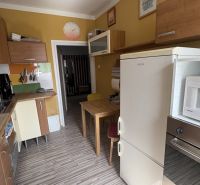 Küche in einer 2-Zimmer-Wohnung mit gelben Wänden und einem Boden in Holzoptik.