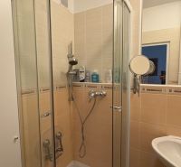 Badezimmer mit Duschkabine in einer 2-Zimmer-Wohnung, Fliesen in Cremefarbe.