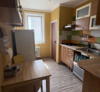 Küche mit gelben Wänden, Holzmöbeln und einem Boden mit Holzdekor in einer 2-Zimmer-Wohnung.