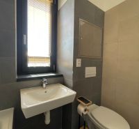 Badezimmer mit Waschbecken, WC und Fenster in einer 2-Zimmer-Wohnung.