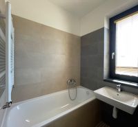 Badezimmer in einer 2-Zimmer-Wohnung mit Badewanne, Waschbecken und Fenster.