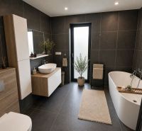 Badezimmer in einem Einfamilienhaus mit Badewanne, Waschbecken und dunklen Fliesen.