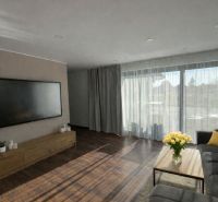 Wohnzimmer in einem Einfamilienhaus mit großem Fernseher, Sofa und Holzboden.