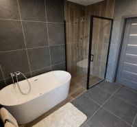 Ein Badezimmer in einem Einfamilienhaus mit freistehender Badewanne und Duschkabine.