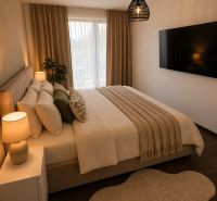Schlafzimmer in einem Einfamilienhaus mit Bett, großem Fernseher und Boden in Holzoptik.