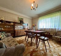 Wohnzimmer im Einfamilienhaus mit antiken Möbeln, Blumendekor und Teppich.