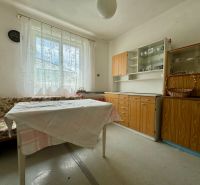 Ein Zimmer in einem Einfamilienhaus mit einem geblümten Sofa, einem Tisch und Holzmöbeln.