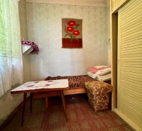 Ein Zimmer in einem Einfamilienhaus mit einem Bett, einem Tisch und einem Einbauschrank, dekorativer Teppich an der Wand.