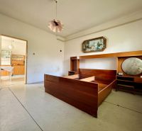 Ein Zimmer in einem Einfamilienhaus mit Retro-Möbeln und einer offenen Tür zur Küche.