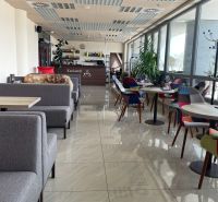Ein modernes Café-Interieur mit bequemen Sitzgelegenheiten und großen Fenstern.