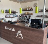 Interieur eines Cafés mit Holzelementen, Theke, Regalen und Kaffeemaschine, optimiert für Gastronomiebereiche.