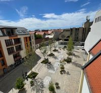 Blick auf den Dreifaltigkeitsplatz in Trnava, mit Gastronomiebereichen und Grünflächen.