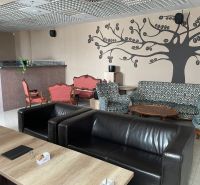 Gasträume mit Ledersesseln, gemusterten Sofas und Wanddekorationen.