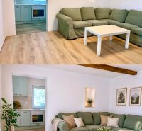Helles Wohnzimmer in einem Einfamilienhaus mit Küche und Sofa, Boden mit Holzdekor.