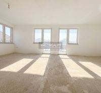 Ein Interieur in einem Einfamilienhaus mit großen Fenstern und einem unfertigen Boden.