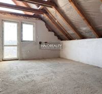 Der Dachboden eines Einfamilienhauses mit freiliegenden Balken und Fenstern, ohne Bodenbelag.