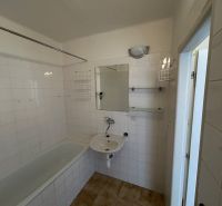 Badezimmer mit Badewanne in einer 2-Zimmer-Wohnung mit Fliesen.