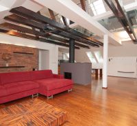 Dachboden-Wohnbereich mit großem rotem Sofa und Holzboden in einer 3-Zimmer-Wohnung.