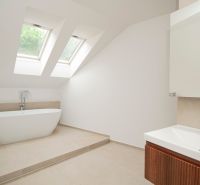 Ein Badezimmer mit Dachfenstern, freistehender Badewanne und Waschbecken in einer 3-Zimmer-Wohnung.