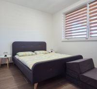 Schlafzimmer mit Bett, Nachttisch und Holzboden in einem Einfamilienhaus.