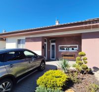 Ein Einfamilienhaus auf dem Feldweg in Dudince mit einem Auto und einem gepflegten Vorgarten.