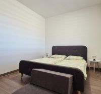 Schlafzimmer im Einfamilienhaus mit Bett und Nachttischen, Boden mit Holzdekor.