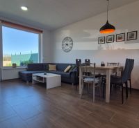 Wohnzimmer in einem Einfamilienhaus mit Holzboden, Sitzgarnitur und Esstisch.