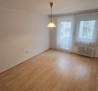 Ein Zimmer in einer 3-Zimmer-Wohnung mit einem Boden in Holzoptik und hängenden Vorhängen.