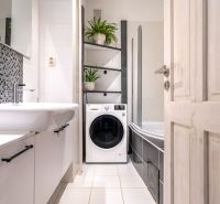 Badezimmer in einer 3-Zimmer-Wohnung mit Waschmaschine, Badewanne und Mosaikfliesen.