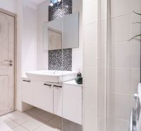 Badezimmer in einer 3-Zimmer-Wohnung mit weißen Fliesen, Waschbecken und Waschmaschine.