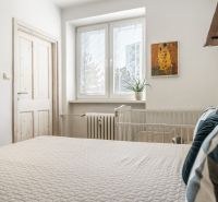 Schlafzimmer in einer 3-Zimmer-Wohnung mit Bett, Pflanze und dekorativem Bild an der Wand.