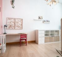 Gemütliches Kinderzimmer mit Holzboden, Schreibtisch und Stauraum.