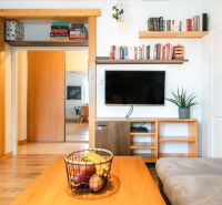 Wohnzimmer mit Fernseher, Büchern und Obst auf dem Tisch, 3-Zimmer-Wohnung mit Holzboden.