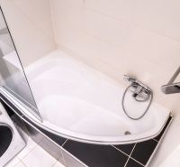 Badezimmer mit Badewanne, Duschabtrennung und Waschmaschine in einer 3-Zimmer-Wohnung.