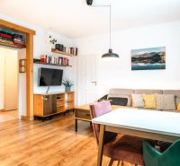Wohnzimmer in einer 3-Zimmer-Wohnung mit Holzboden, bequemer Couch und Fernseher.