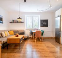 Wohnzimmer mit Holzboden, Sofa und Esstisch in einer 3-Zimmer-Wohnung.