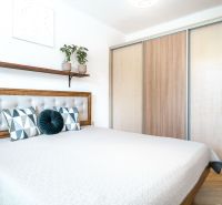 Schlafzimmer mit Bett, Einbauschrank und Boden mit Holzdekor in einer 3-Zimmer-Wohnung.