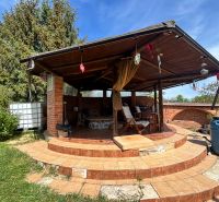 Überdachte Terrasse bei einem Einfamilienhaus in Veľké Chlievany mit Ziegelverkleidung und Treppen.