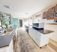 Küche in einem Einfamilienhaus mit langer Arbeitsplatte, Spüle und Treppe.