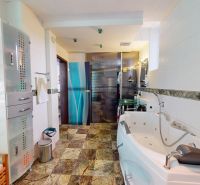 Badezimmer mit Eckbadewanne, Glasfliesen und Waschbecken in einem Einfamilienhaus.